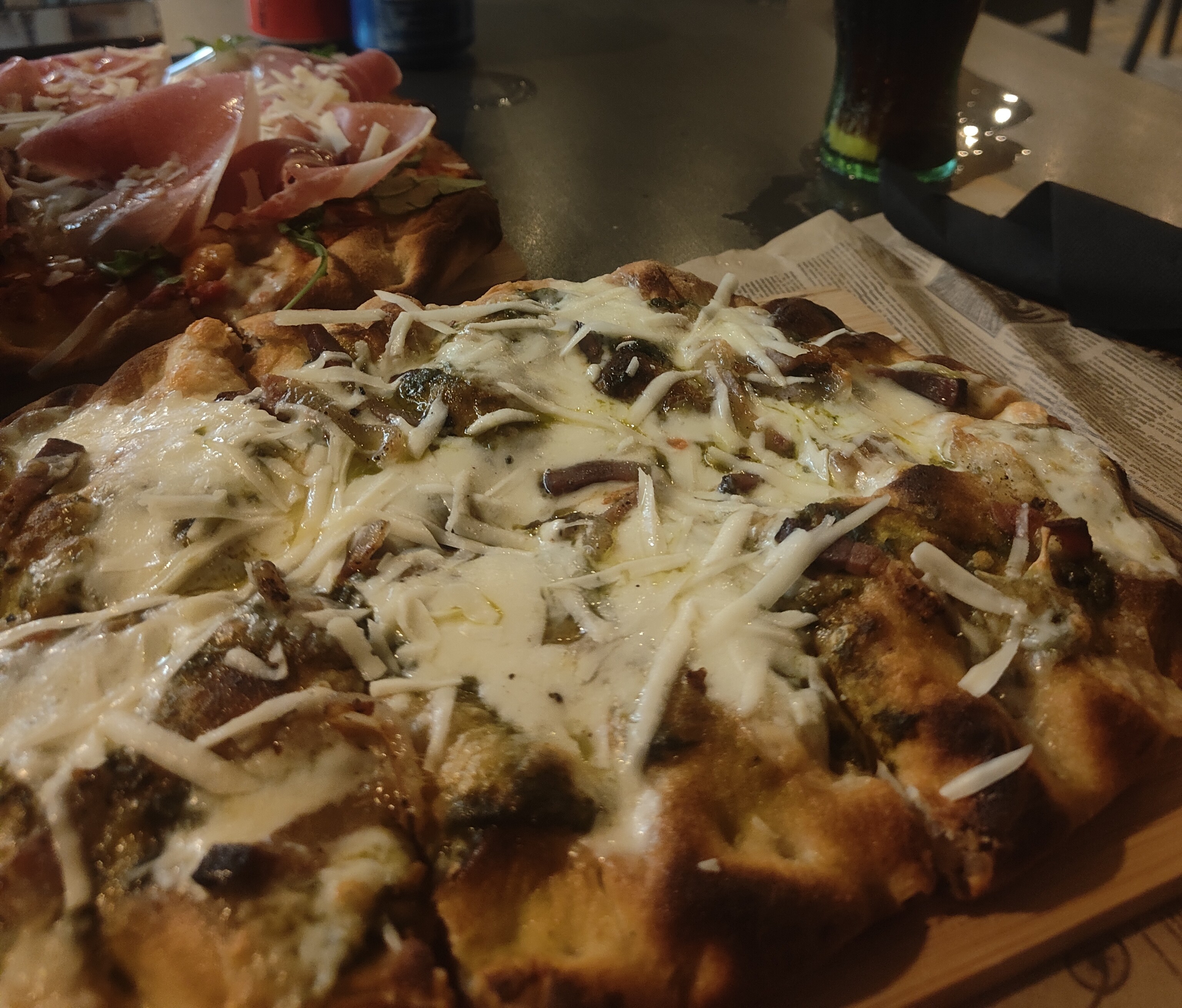 Pinsa con queso rallado sobre una tabla de madera, de noche en la terraza