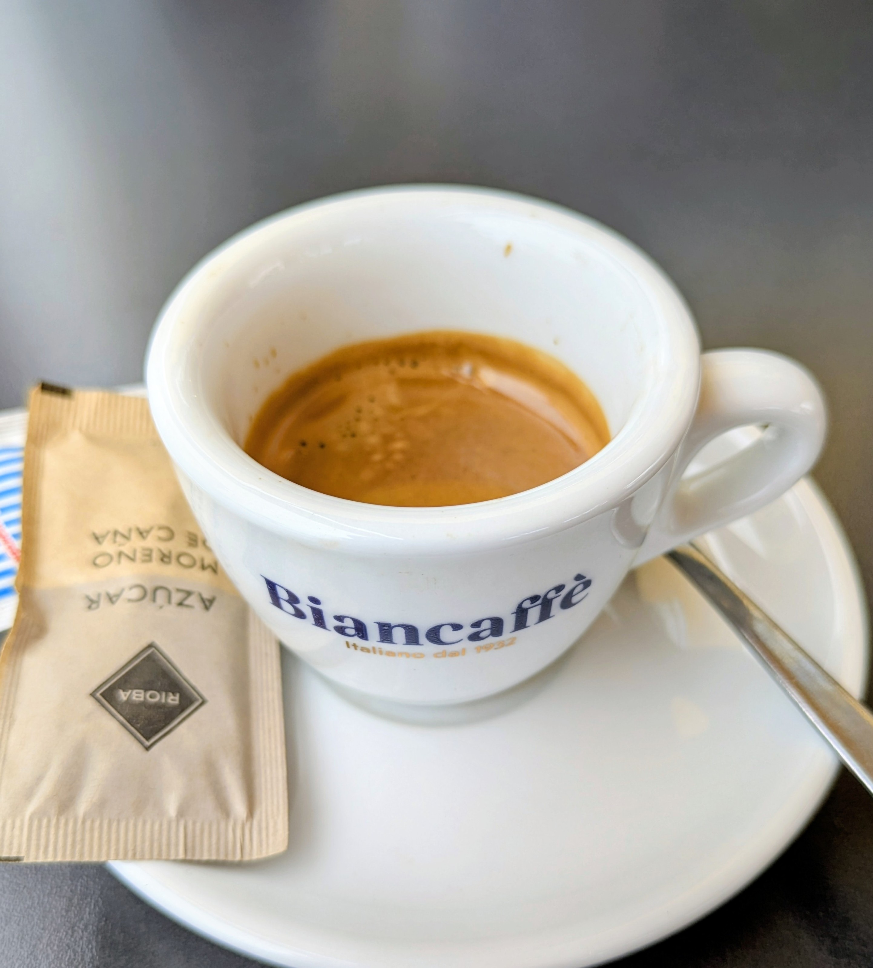 Un café espresso en taza blanca con azúcar moreno